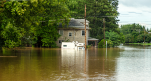 A home is surrounded by deep, brown flood water.